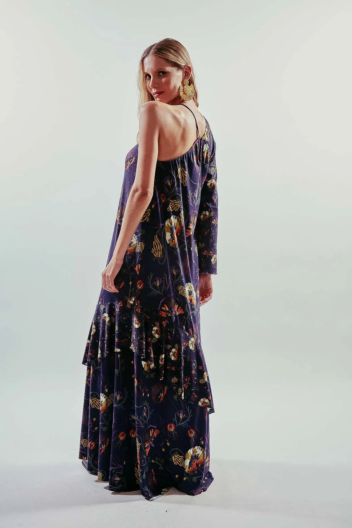 Vestido largo liso y asimétrico de una manga larga, color azul oscuro, con vuelo y volantes