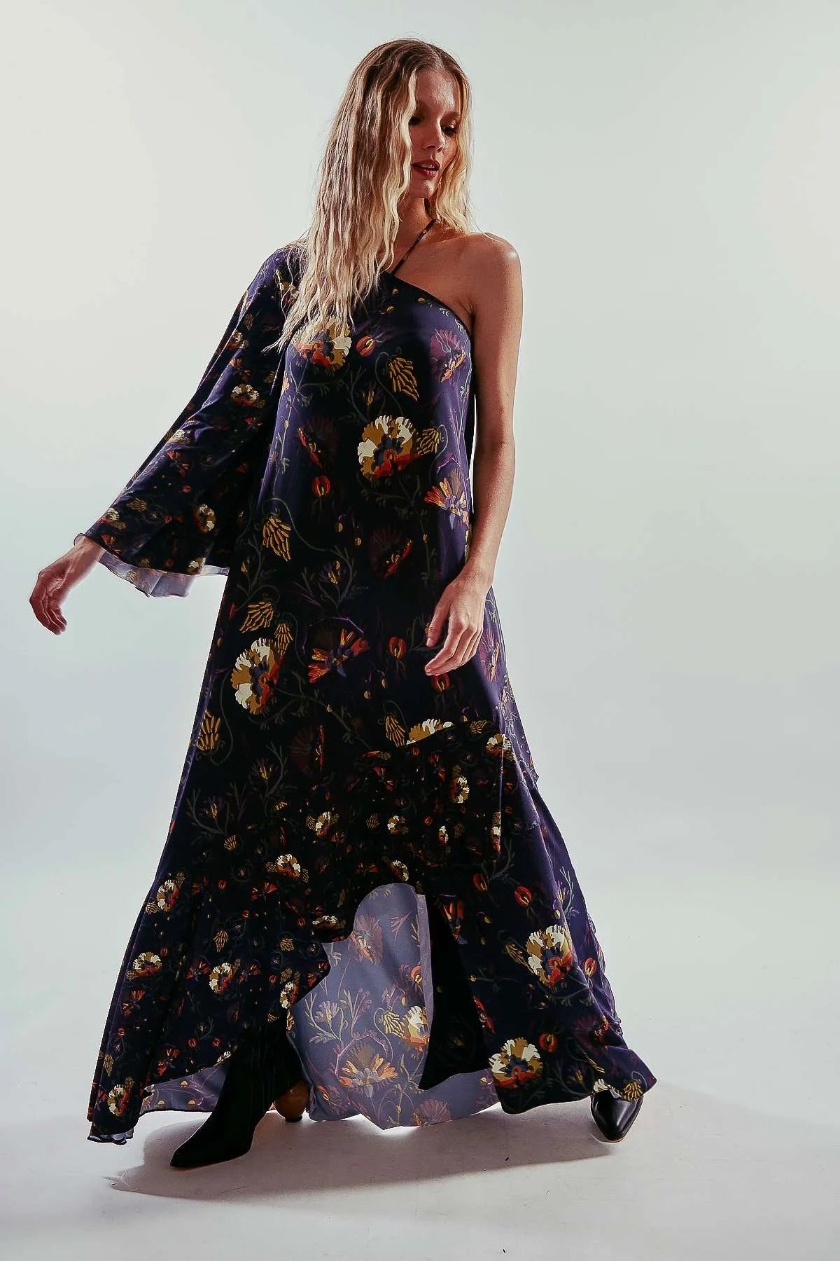 Vestido largo liso y asimétrico de una manga larga, color azul oscuro, con vuelo y volantes
