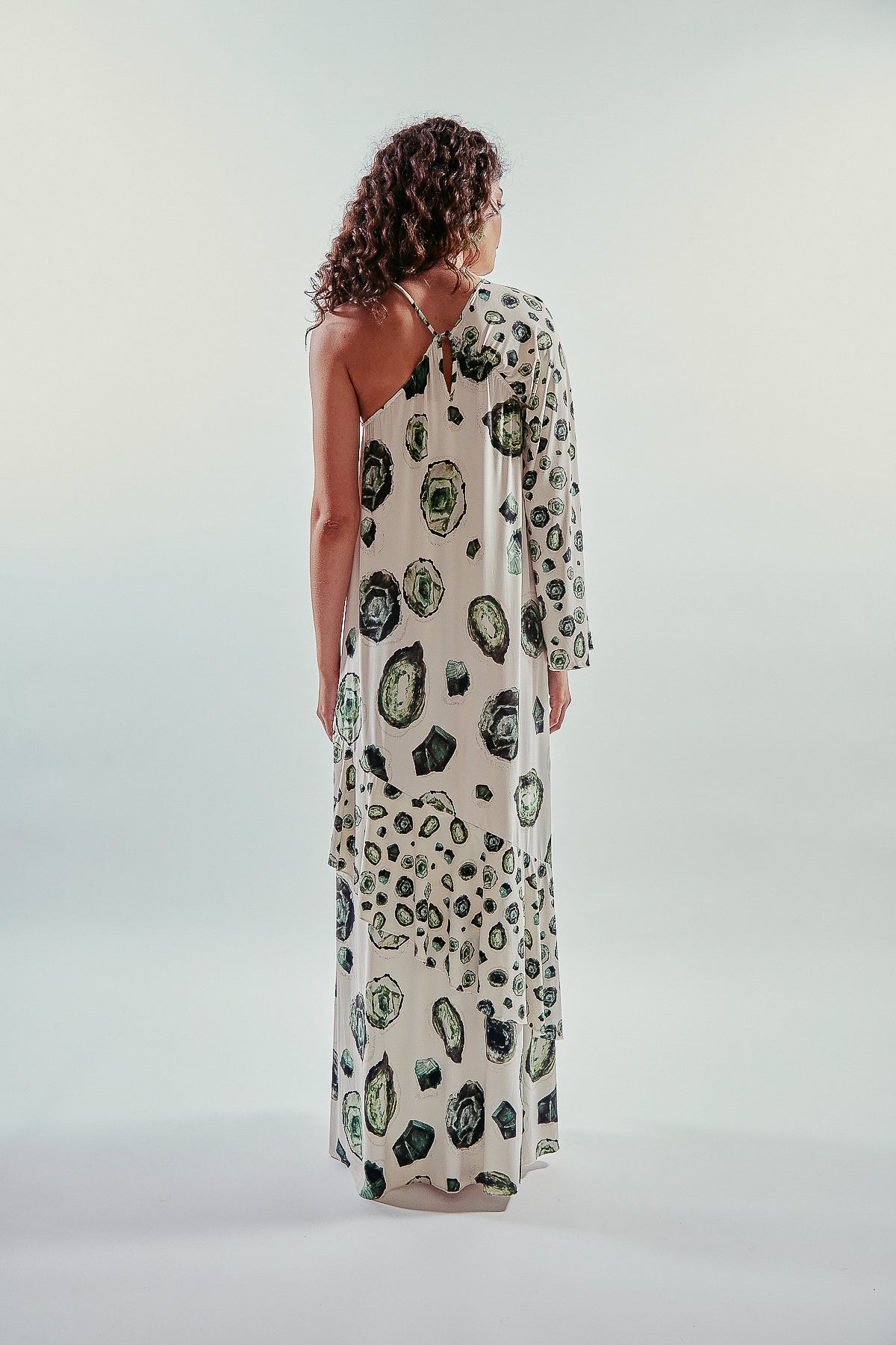 Vestido largo y asimétrico de una manga larga, estampa esmeraldas, con vuelo y volantes