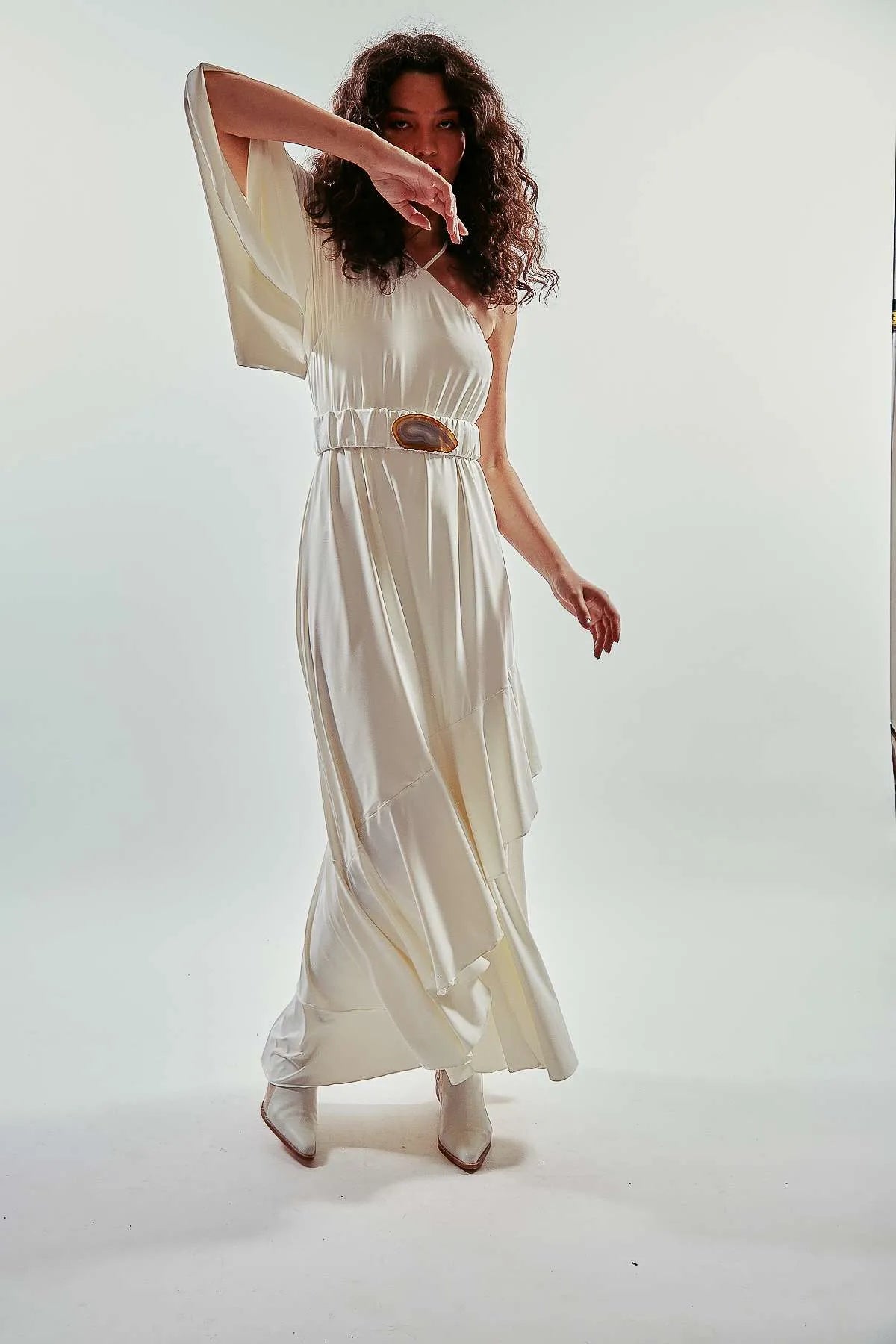 Vestido largo liso y asimétrico de una manga larga, color blanco, con vuelo y volantes