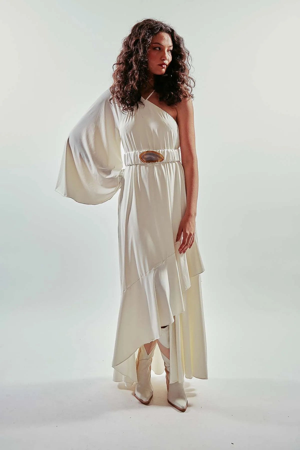 Vestido largo liso y asimétrico de una manga larga, color blanco, con vuelo y volantes