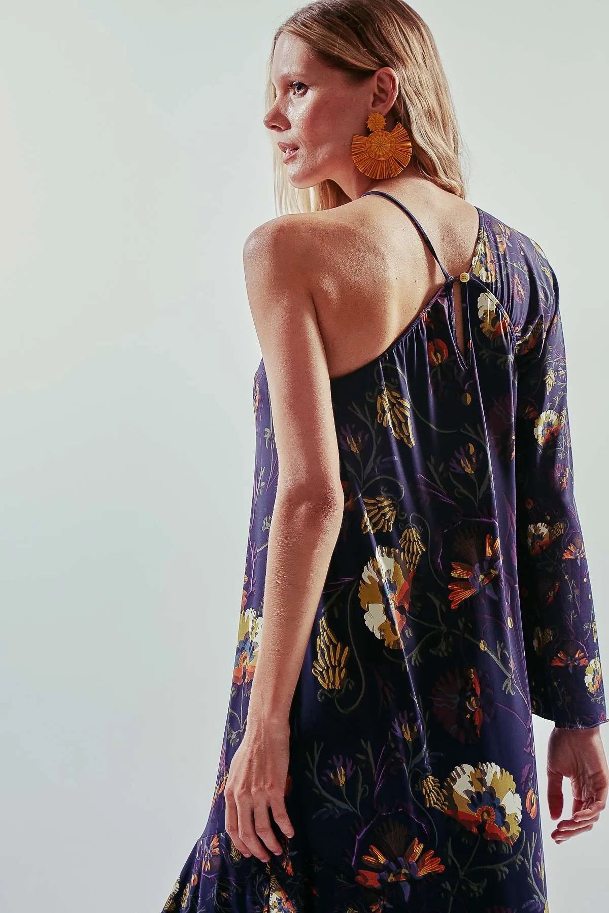 Vestido largo liso y asimétrico de una manga larga, color azul oscuro, con vuelo y volantes